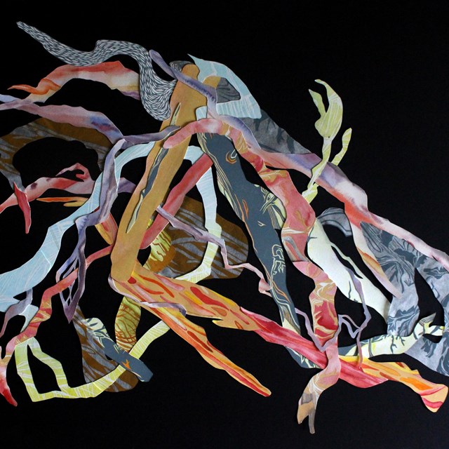 Layers of paper with different patterns and colors, each piece cut into twisted and branching shapes