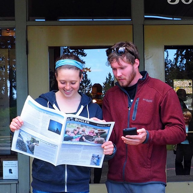 Two visitors look over the Buglar in front of the Visitor Center.