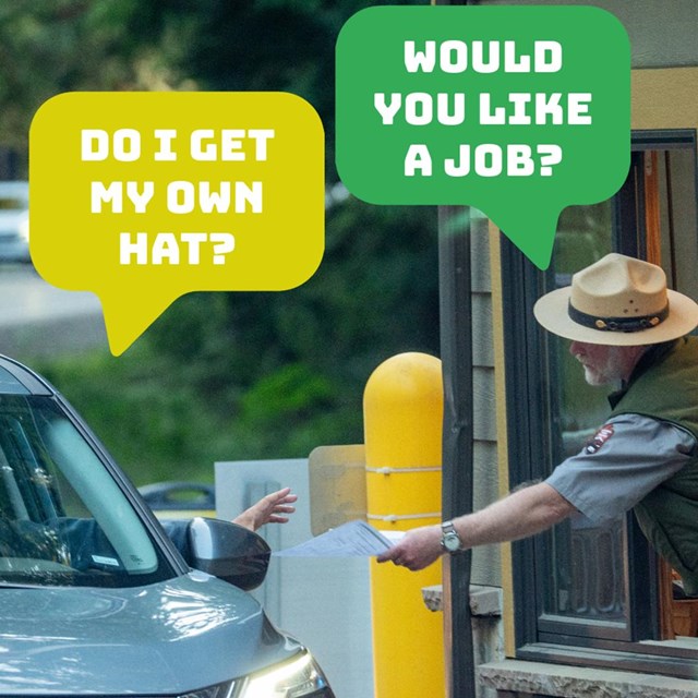 A park ranger leans out of a fee booth to take a piece of paper from someone in a car. 