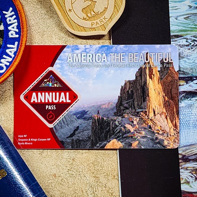A plastic card labeled “America the Beautiful Annual Pass” with a photo of mountains.ntai