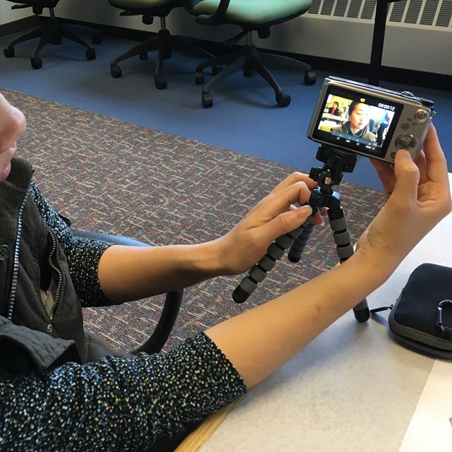 A person looks at the playback image in the viewfinder of a camera mounted on a small tripod.