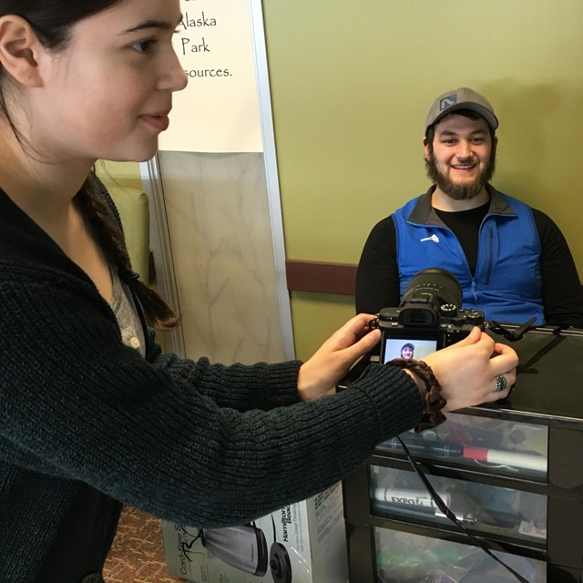 A workshop participant points a camera at a seated participant, whose image is displayed onscreen.