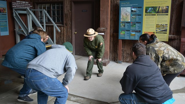 Ranger demonstrating the "cave walk" to visitors.