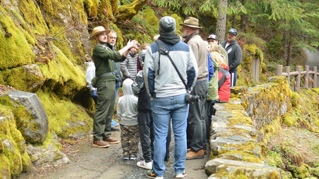 A park ranger talking to a group of people outside of the cave entrance.