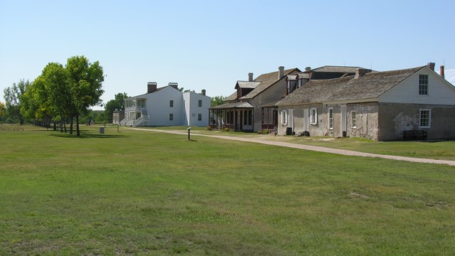 Historic wooden fort sitting in a grassy field.