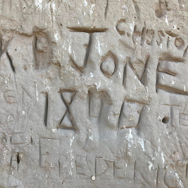 Names scratched into a rock wall.