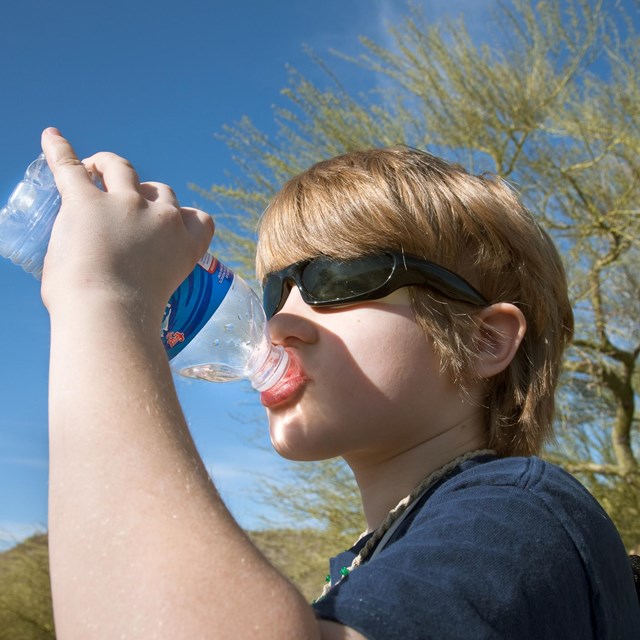 Child drinking water in the hot sun