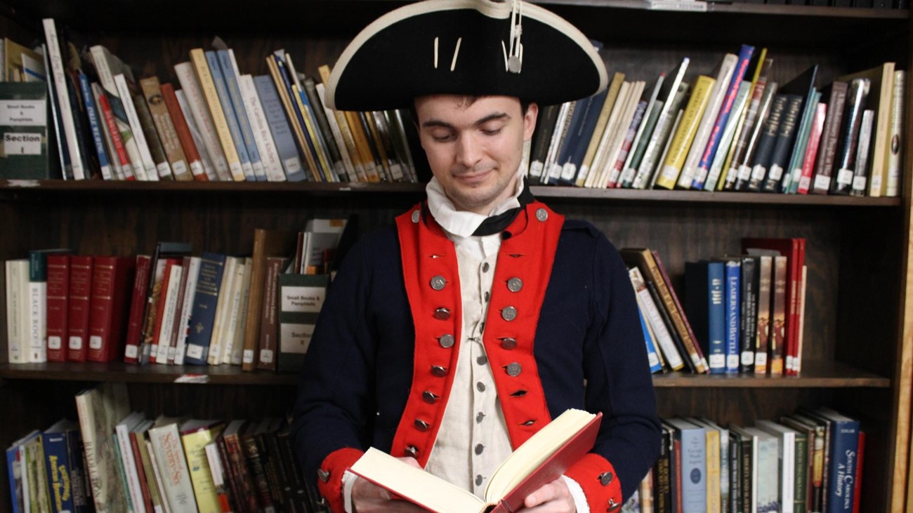 Reenactor reads a book dressed as a Continental soldier.