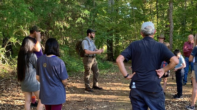 Ranger stands surrounded by listening visitors.