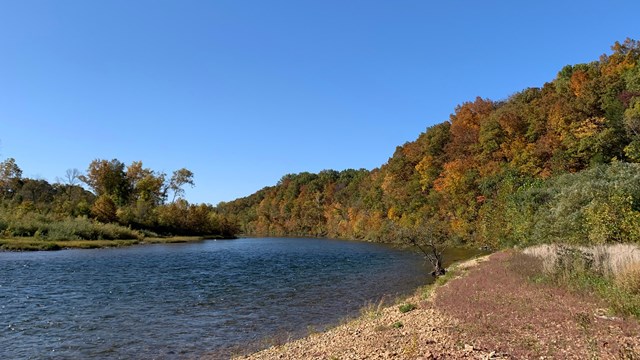 A river flows towards a hill then curves out of view.