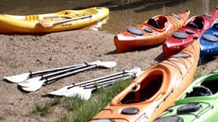 empty bright colored kayaks beached on the gravel bar