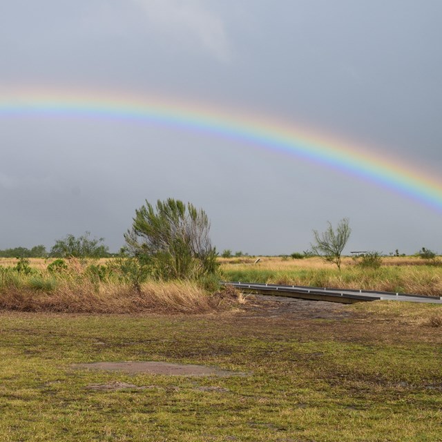 A rainbow arches over the prairie.