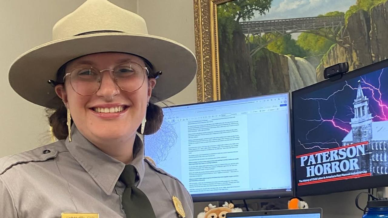 A female ranger Standing facing towards the camera smiling with computer screen in the background