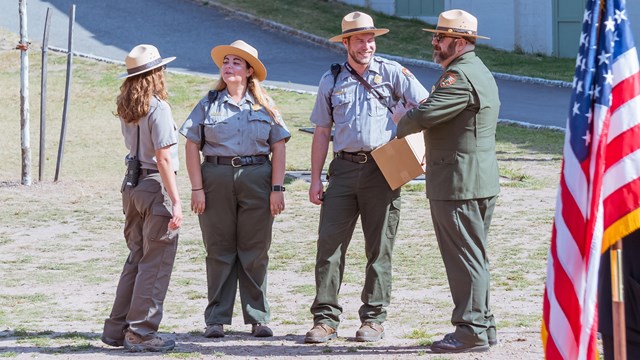 Park rangers stand in a group near an American flag