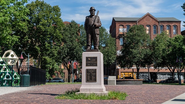 A statue of Lou Costello stands beside a playground