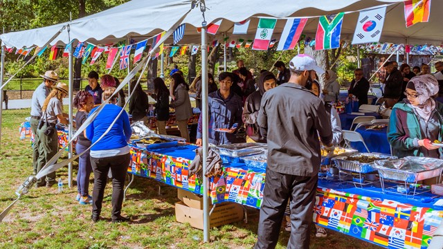Park rangers & visitors gather food in an outdoor ethnic buffet tent