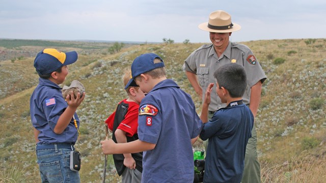 A group of cub scouts talk with a ranger on a hike. 