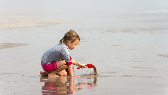 A young child digs in the sand.