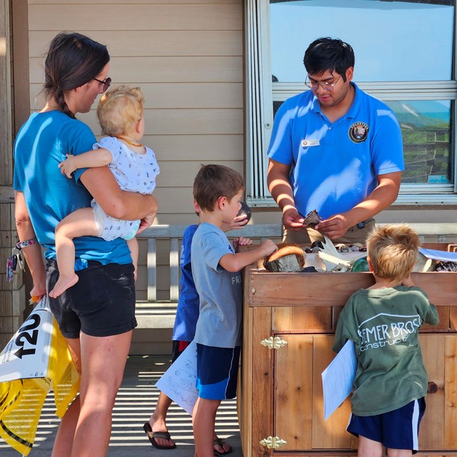 A park intern tell a group of children about shells that are found on the beach.