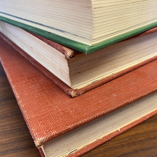 A stack of three old books.