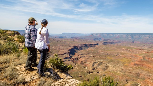 Two hikers at a scenic overlook, looking out across the mesas and canyons from Whitmore Point.