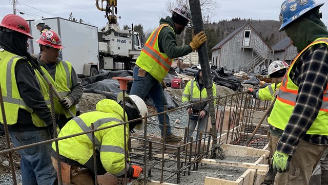 Staff work to pour fresh concrete using a cement pump.