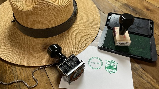 Rubber cancellation stamps and ink pad next to a ranger flat hat. 