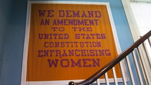 a women's suffrage banner hangs in a staircase at Belmont Paul Women's Equality National Monument