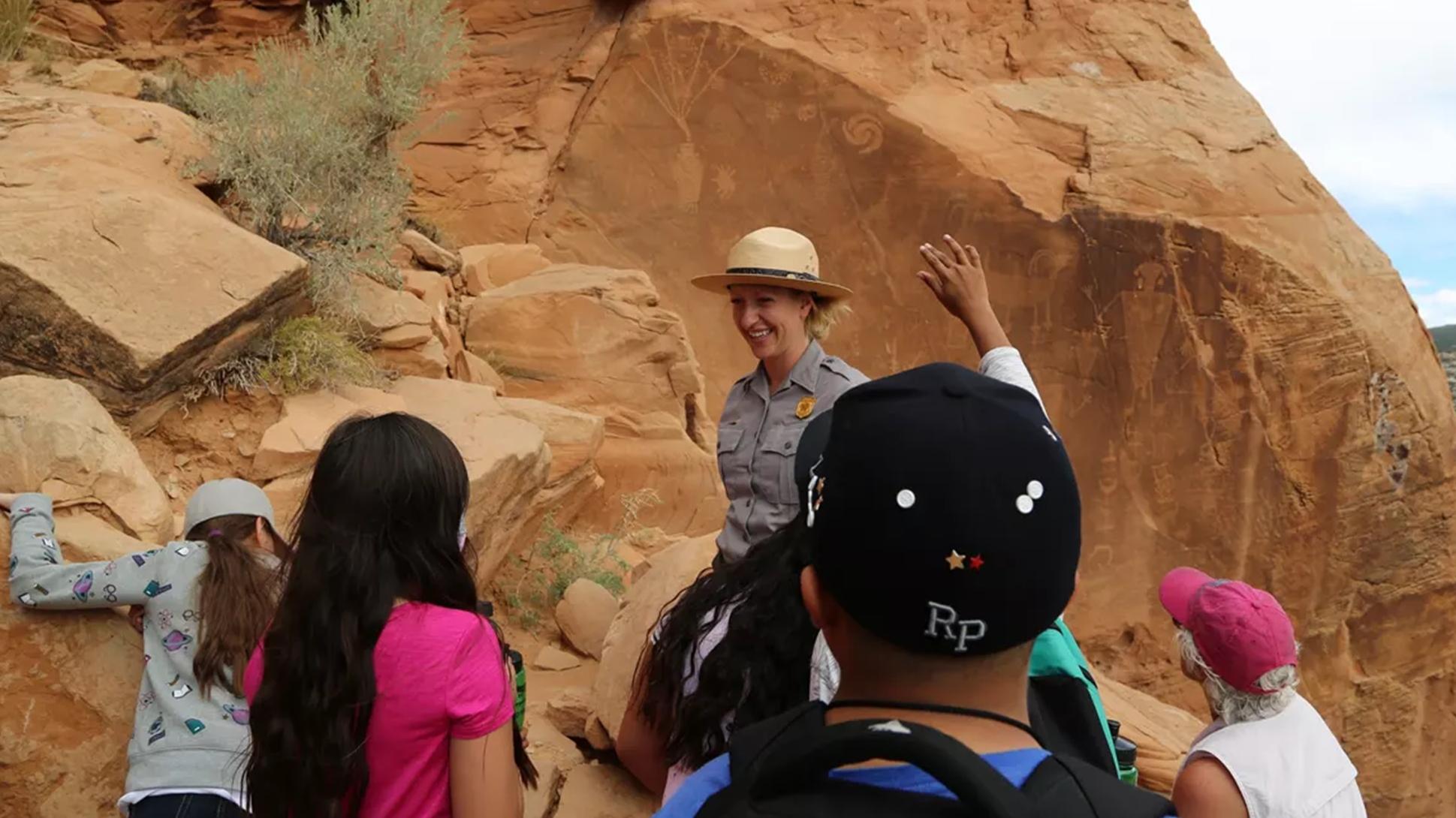 Park ranger talking to school kids with raised hands