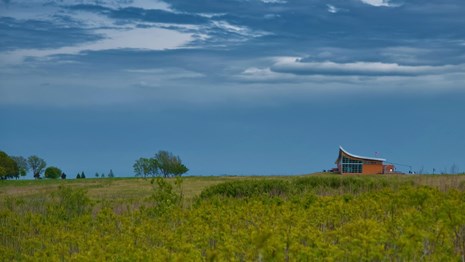 The peak of the roof of the Homestead NMA Heritage Center in view across a sea of green.