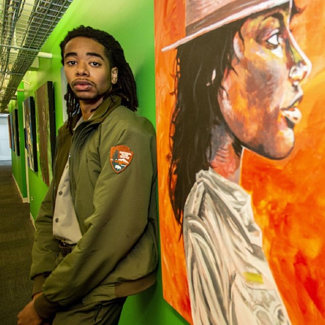 Park ranger standing next to his painting of a park ranger