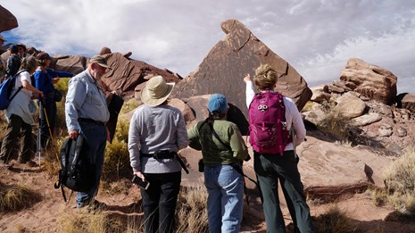 A volunteer interpreter leads a group along a pale ridge in the Painted Desert