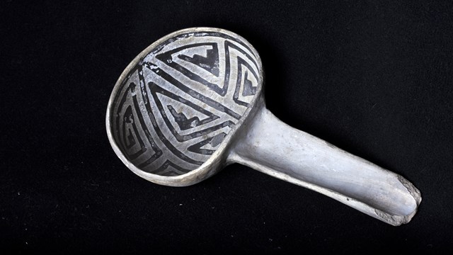 Ancient black on white ladle artifact on a black background