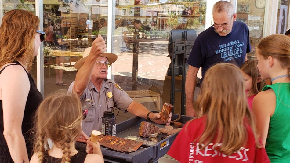 Visitors surround a touch table to listen to Ranger Jack
