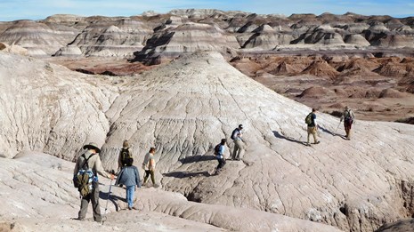 Hikers explore the route to Red Basin through colorful badlands