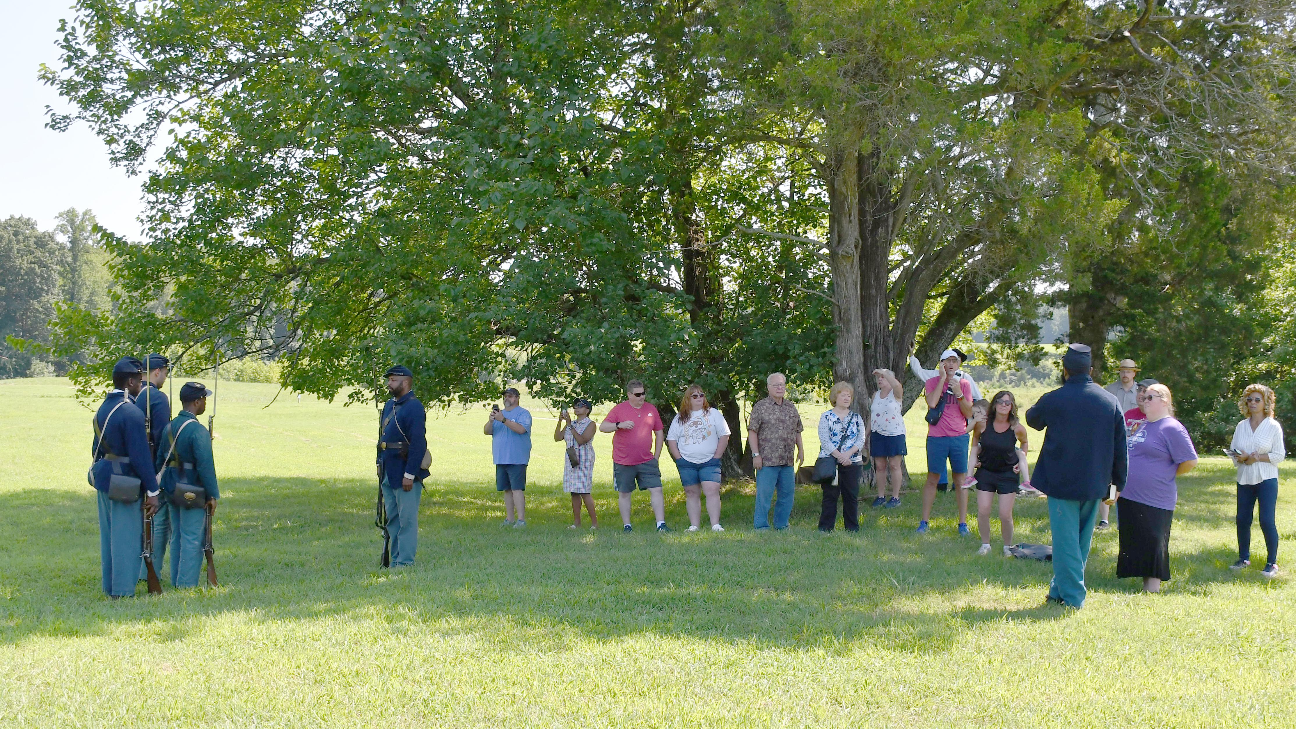 A crowd of people watch a four black men dress in US Civil War Uniforms
