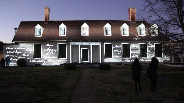 Names of enslaved people projected on a house.