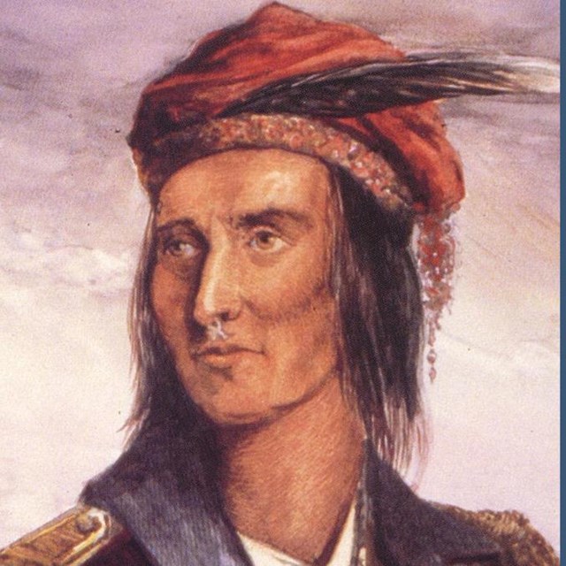 Native American man wearing a read beret and red jacket with gold epulets