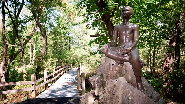Statue of George Washington Carver as a boy on wooded trail