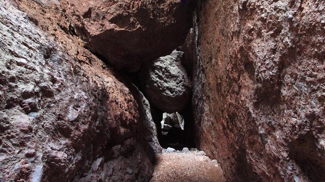 Large boulder suspended by red rock walls on either side.