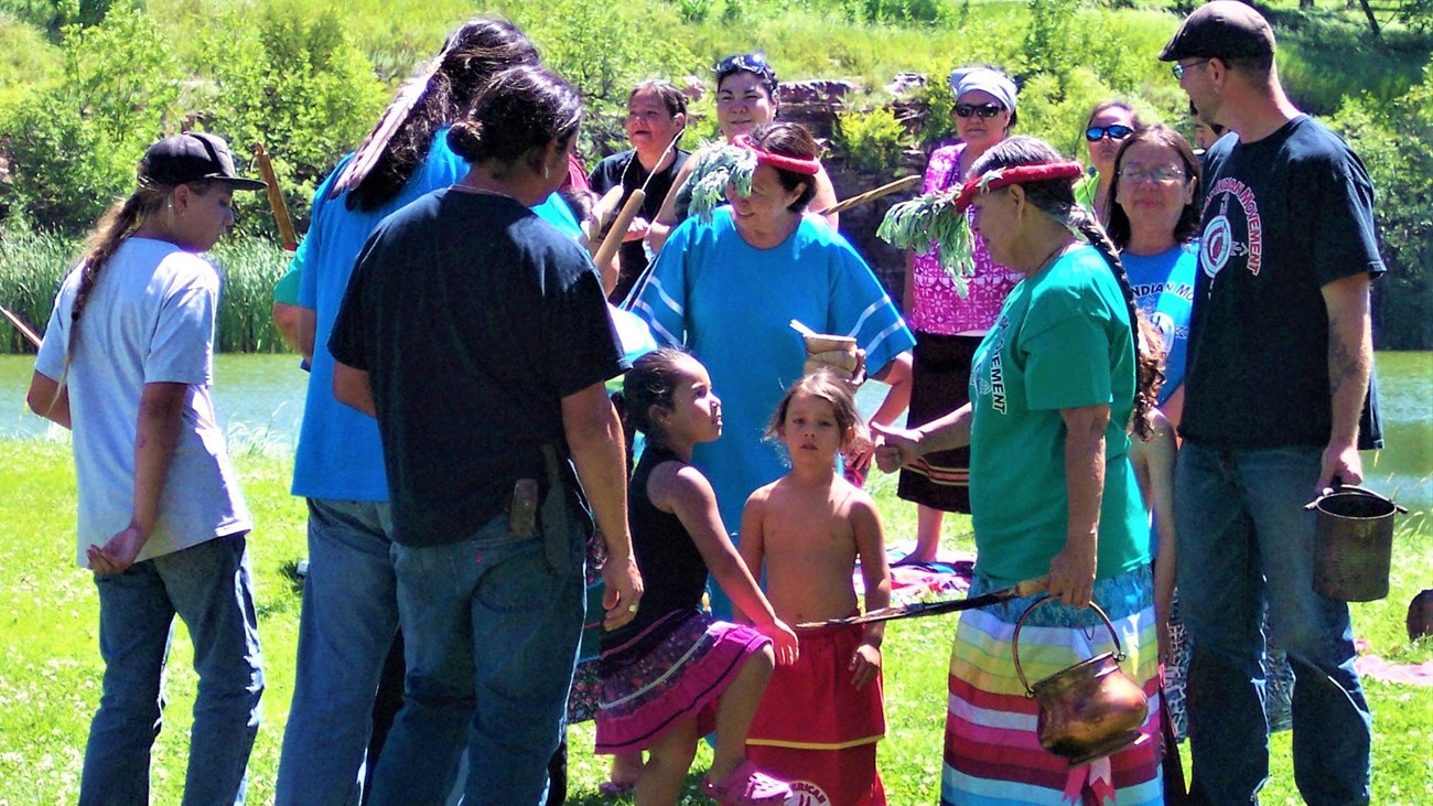 A group of people gathered on the grass around a couple kids