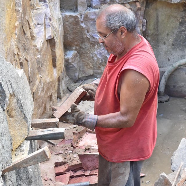 A man holding a stone inside a quarry pit