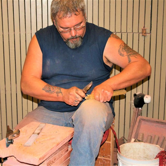 A man carving a pipe stem out of wood