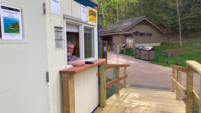 A ranger pokes their head out of a fee collection booth.