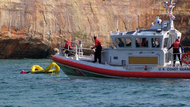 A coast guard rescue boat picks up a group from Lake Superior in a life raft.
