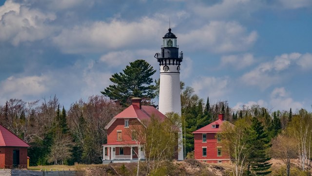 A lighthouse with a white tower and red brick quarters