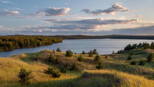 A lake at sunset with green grass and clouds.