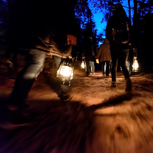Visitors carrying lanterns during sunset lighthouse program.