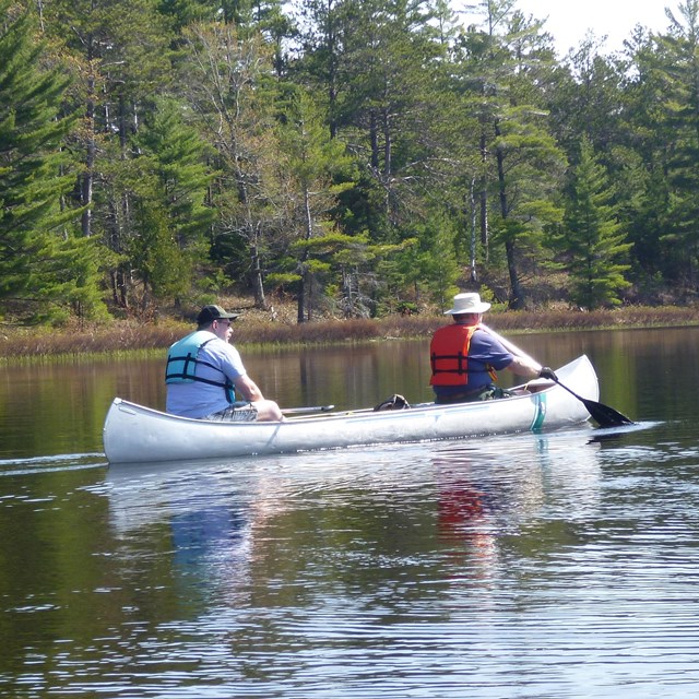 Two people in a canoe on an inland lake.