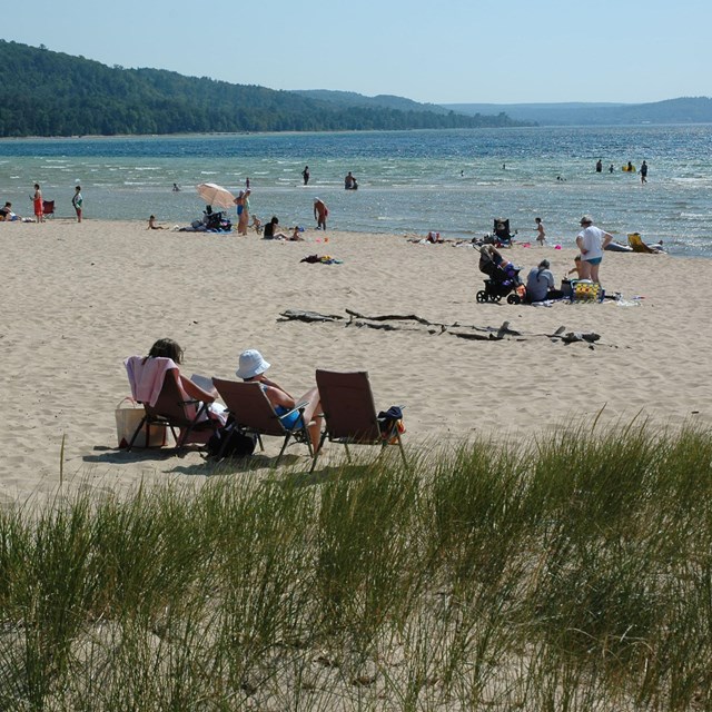 Sunbathers and swimmers at the Sand Point Beach on a summer day.